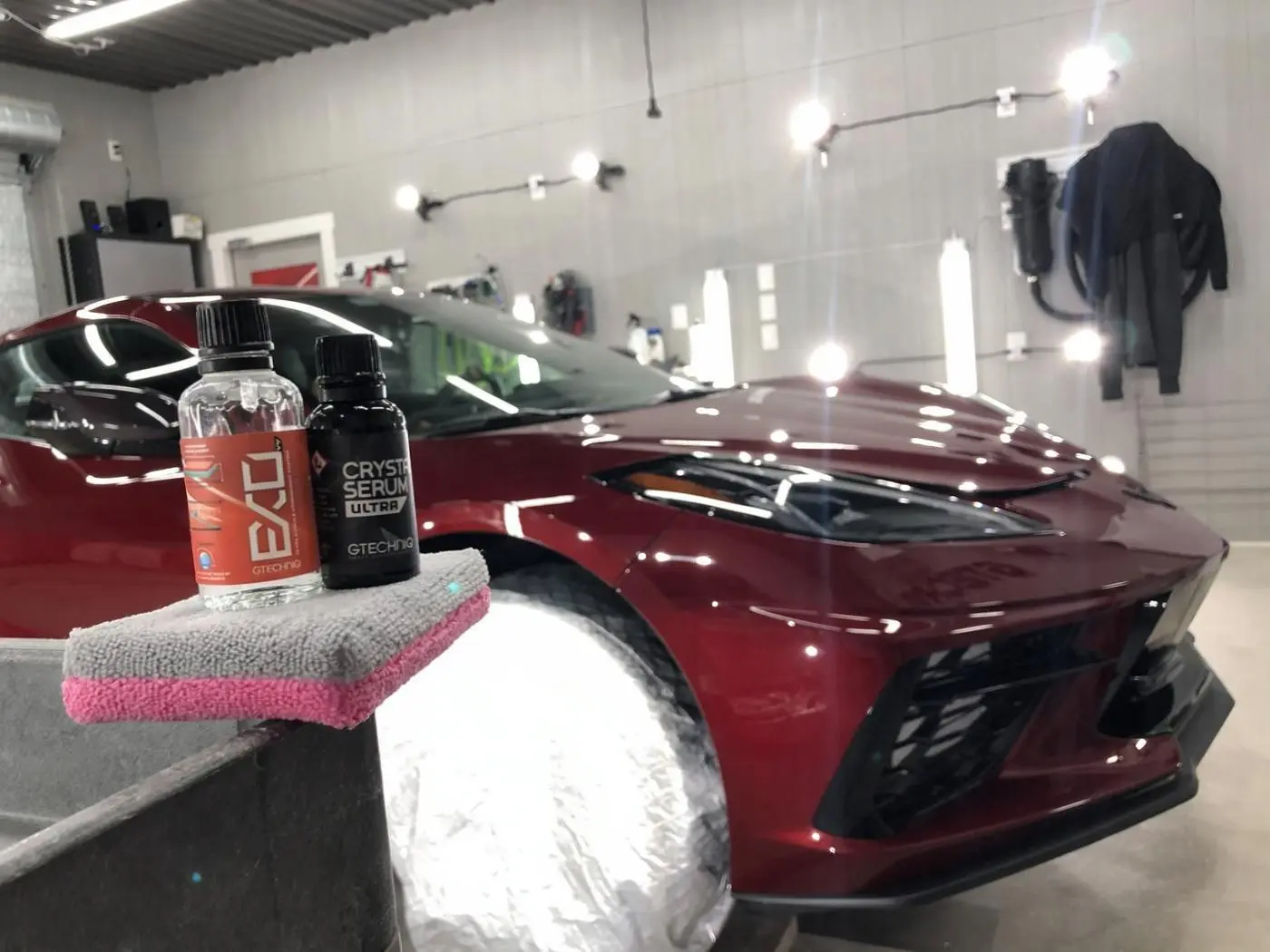 Ceramic coating bottles and applicator in front of a red Corvette
